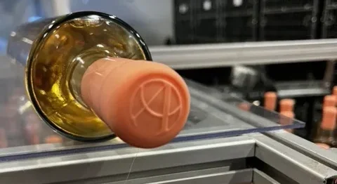 Capsule de cire saumon frappée d'un monogramme sur une ligne d'embouteillage